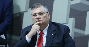Flávio Dino com expressão pensativa e mão no queixo