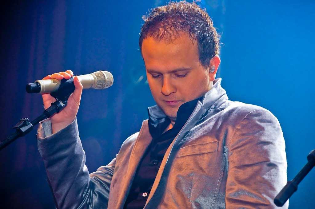 Matheus Possebon olhando para baixo e segurando microfone