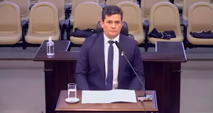Sergio Moro sentado em cadeira, olhando pra frente com expressão séria
