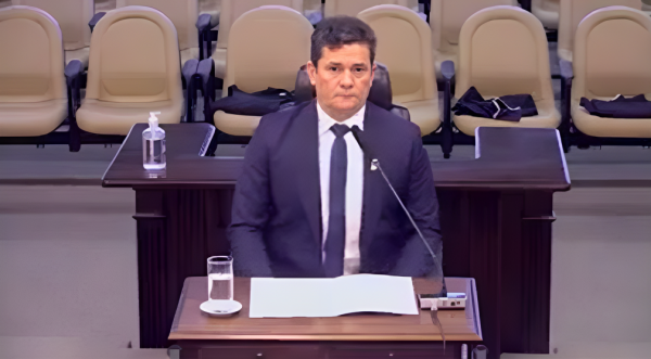 Sergio Moro sentado em cadeira, olhando pra frente com expressão séria