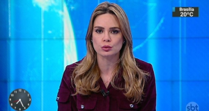 Rachel Sheherazade de roupa cor de vinho, falando para a câmera em estúdio de telejornal, de cabelo solto