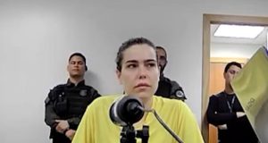 Amanda Partato com expressão triste e camiseta amarela, com cabelo preso