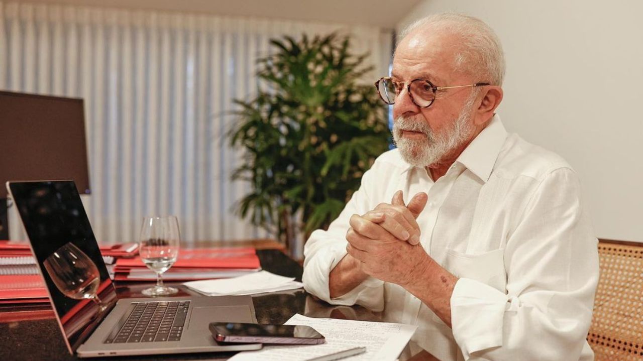 Lula em frente a notebook com roupa branca e expressão séria