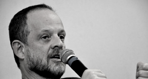 Breno Altman de perfil, falando em microfone, em foto em preto e branco
