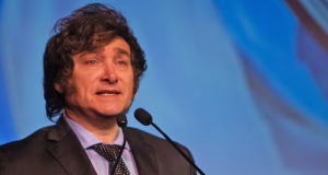 Javier Milei falando em microfone com expressão séria