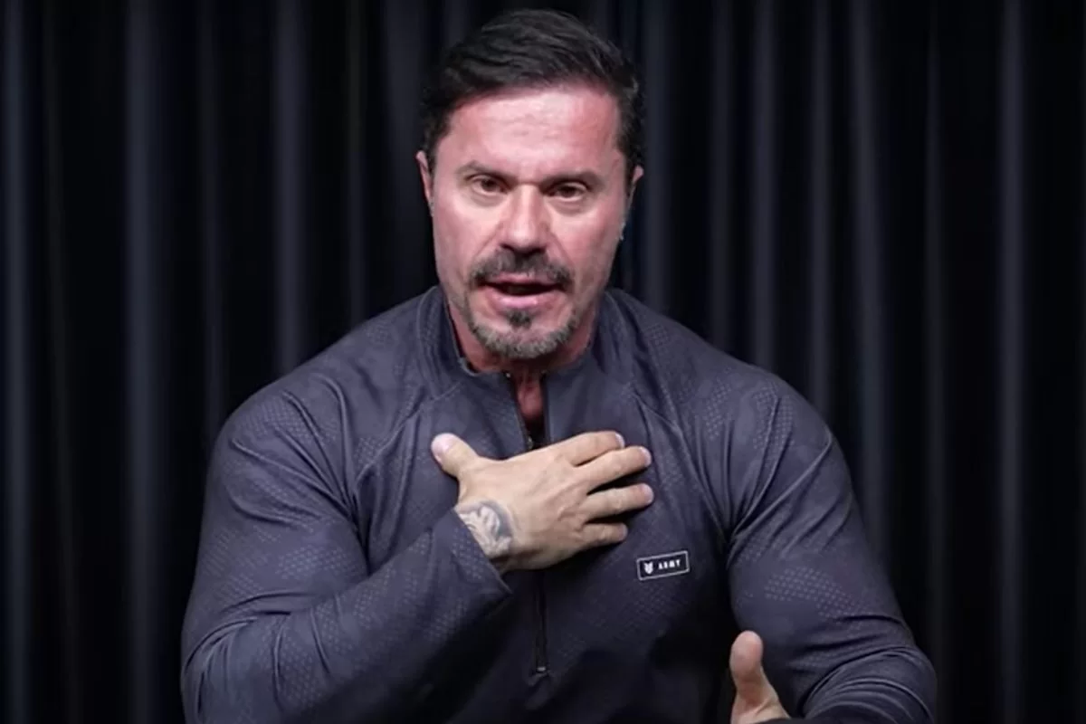 Renato Cariani de roupa cinza, falando e gesticulando com expressão séria