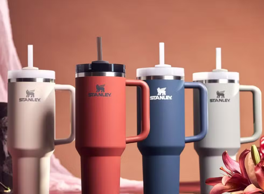 Copos da Stanley em quatro cores diferentes com fundo vermelho