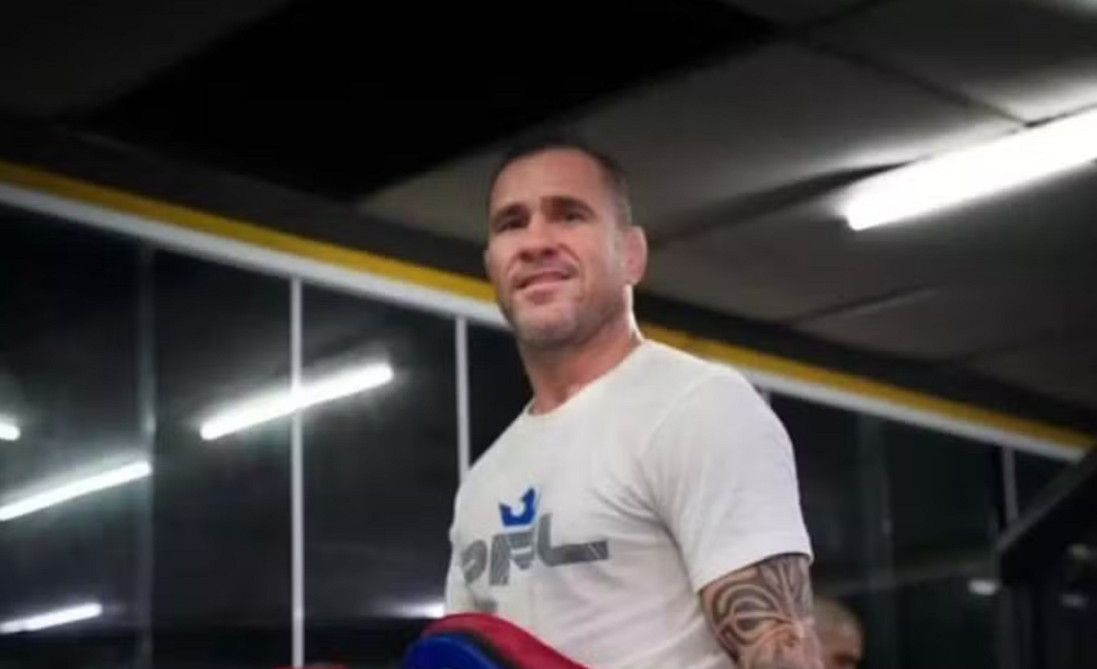 Diego Braga sorrindo de maneira tímida, de camiseta branca