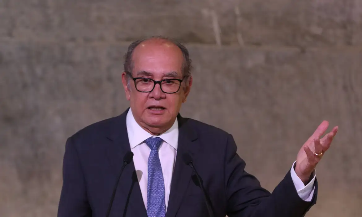 Gilmar Mendes falando em microfone com expressão séria e gesticulando