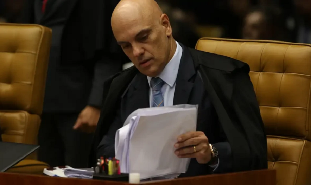 Alexandre de Moraes de cabeça baixa lendo papéis