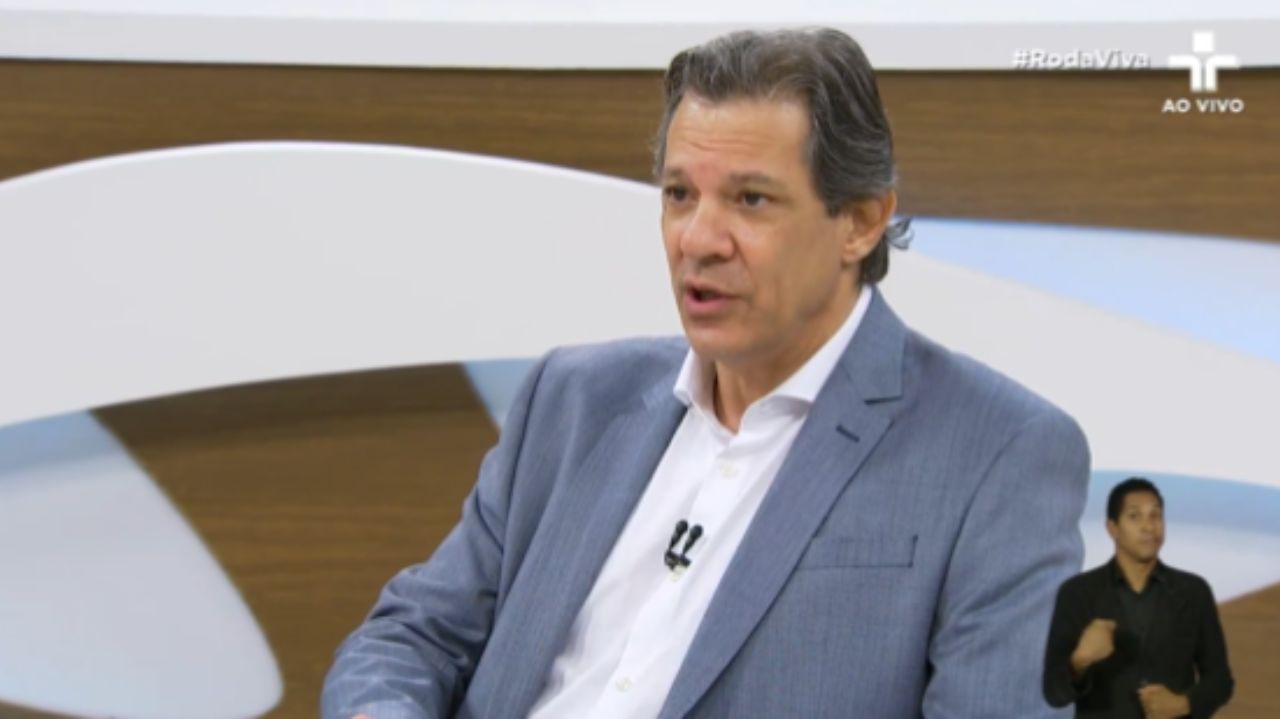 Fernando Haddad falando com expressão séria no estúdio do Roda Viva