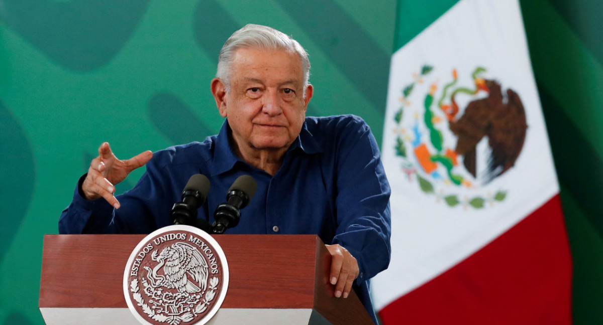 Obrador com camisa social azul escura, falando em microfone e gesticulando