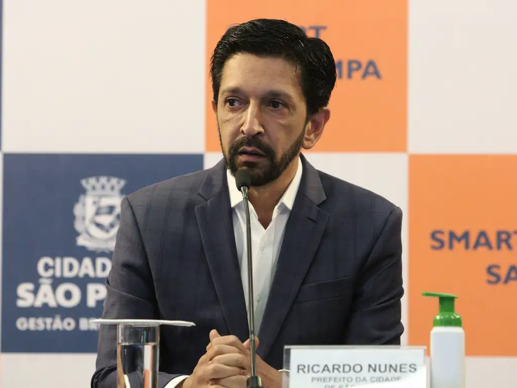 Ricardo Nunes olhando para o lado com expressão assustada, perto de microfone