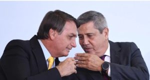 Jair Bolsonaro e General Braga Netto cochichando com expressões de riso e rostos próximos