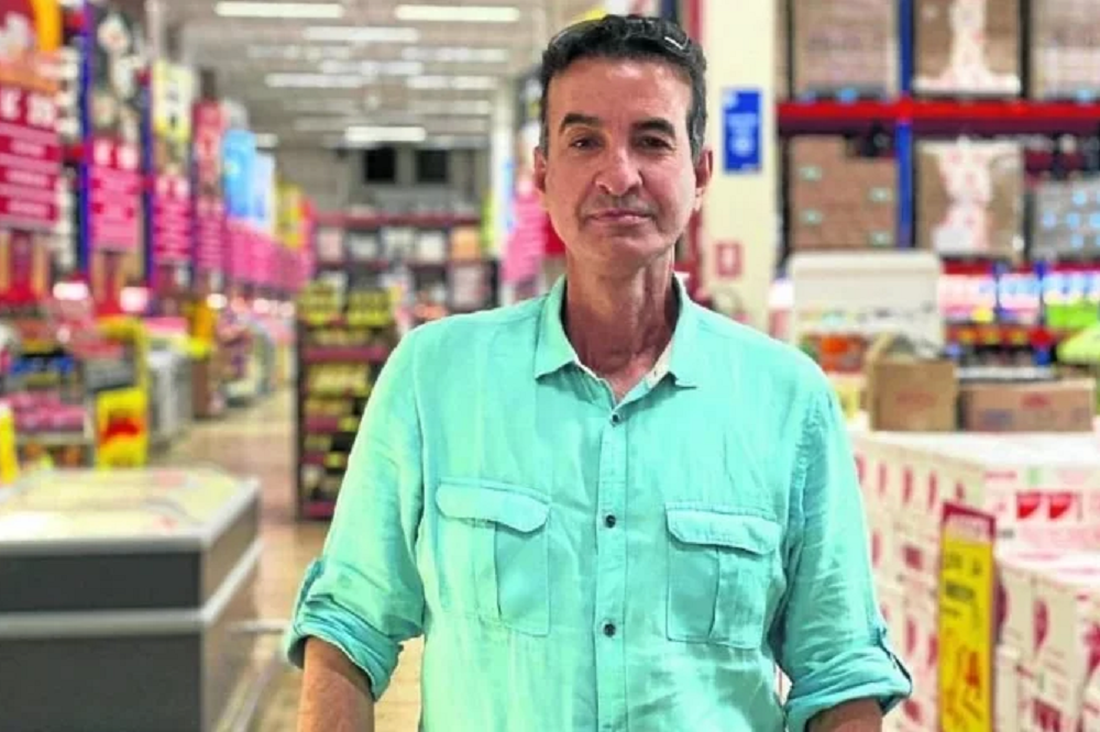 Adauto de Mesquita de camisa social verde, com expressão séria, em supermercado
