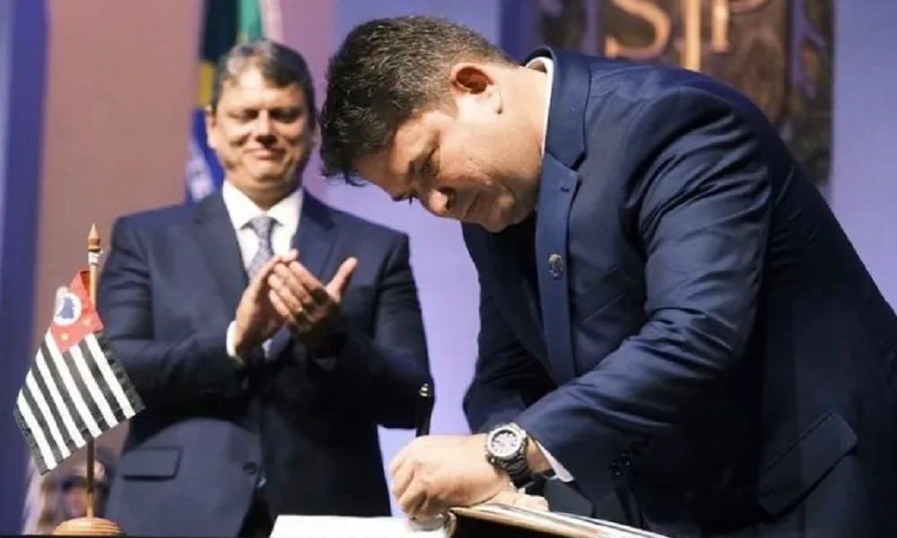 Arthur Lima assinando papel enquanto é aplaudido por Tarcísio de Freitas