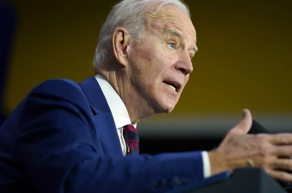 Joe Biden de perfil, falando e gesticulando com expressão séria