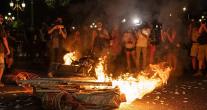 Colchão pegando fogo na rua com manifestantes em volta