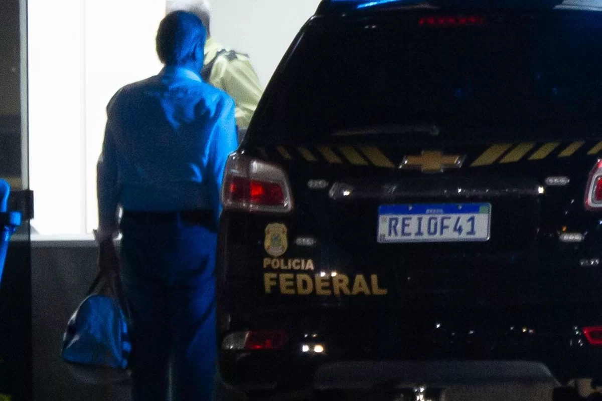 Valdemar Costa Neto de costas e em pé, ao lado de carro da PF