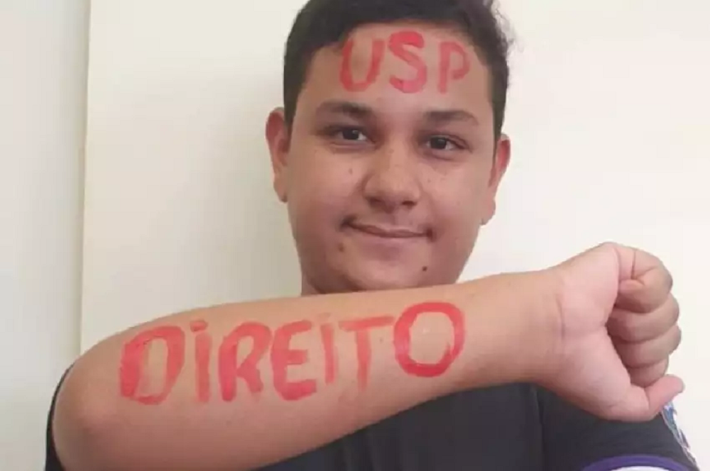 Glauco Dalalio do Livramento com testa e braços pintados de vermelho com as palavras "USP" e "Direito"