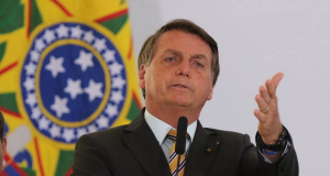 Jair Bolsonaro apontando pra frente com expressão séria