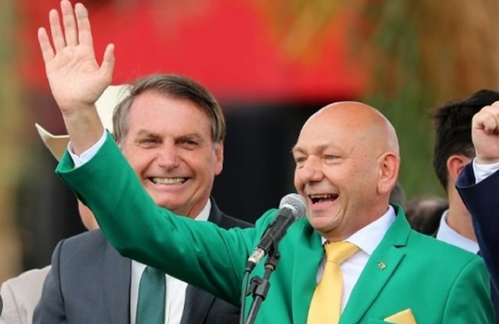 Jair Bolsonaro sorrindo e Luciano Hang sorrindo e acenando