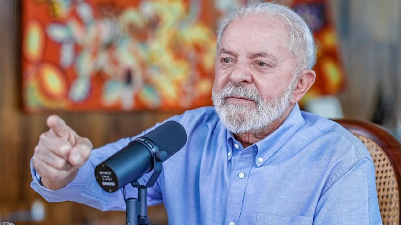Lula de roupa social clara, falando e apontando pra frente com expressão séria