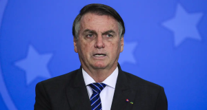 Jair Bolsonaro com expressão desconfiada e mão no peito
