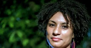 Marielle Franco posando para foto com expressão séria, perto de plantas