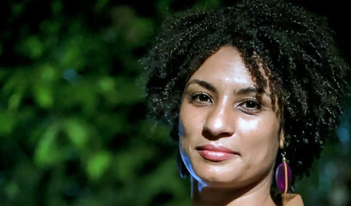 Marielle Franco posando para foto com expressão séria, perto de plantas