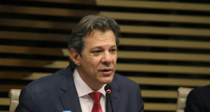 Fernando Haddad falando com expressão séria, sem olhar pra câmera, de roupa social