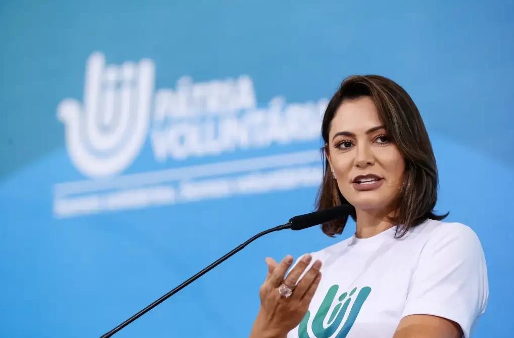 Michelle Bolsonaro de camiseta branca, falando e gesticulando