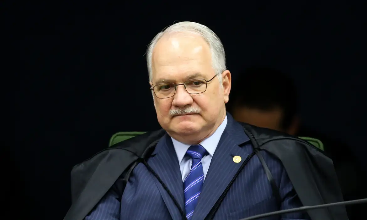 Edson Fachin com roupa azul escura e óculos, com expressão séria