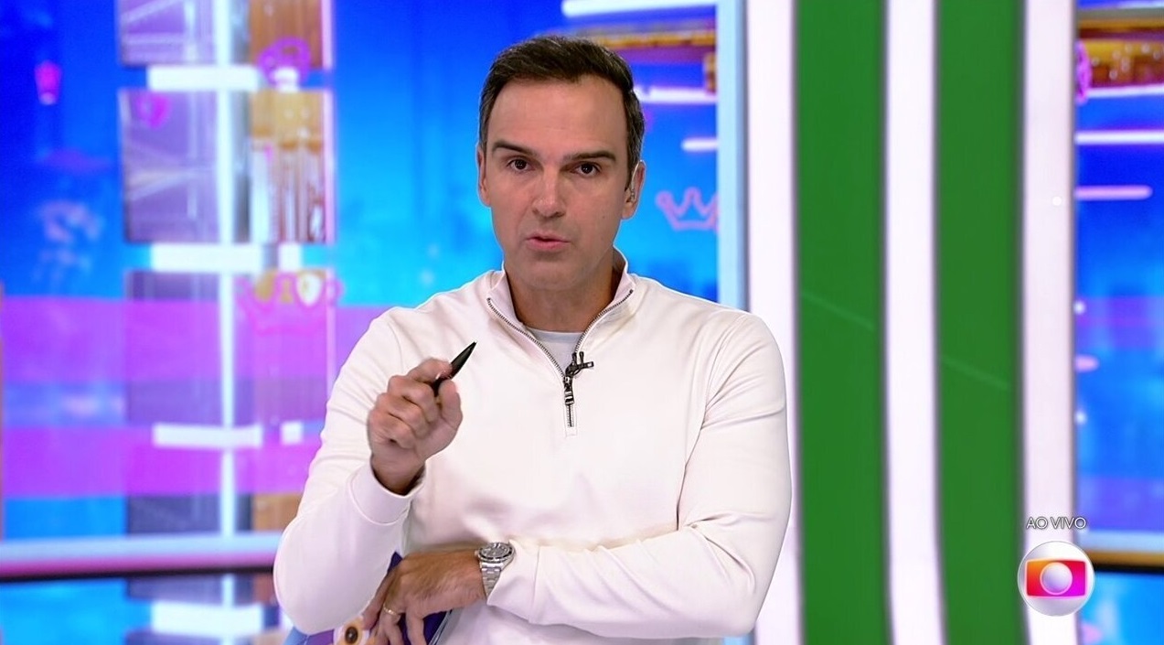 Tadeu Schmidt de blusa branca, falando e apontando para a câmera