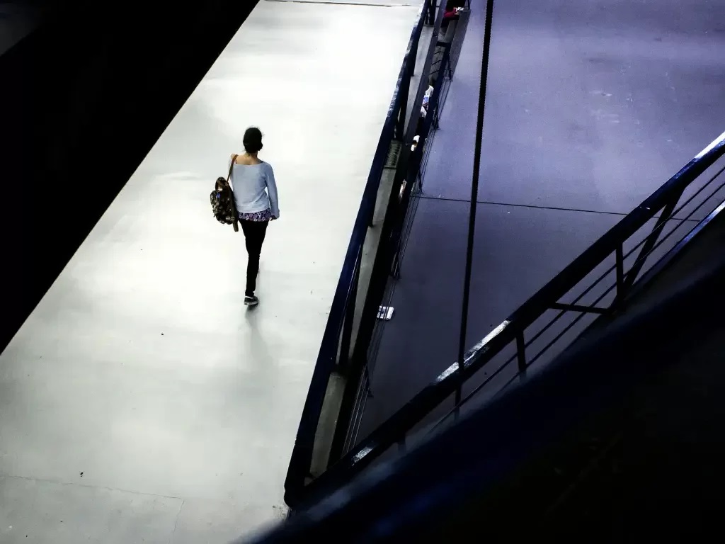 Mulher de costas, carregando mochila, caminhando à noite sozinha