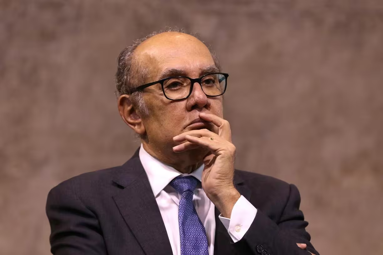 Gilmar Mendes de roupa social e óculos, com expressão pensativa e mão no rosto