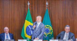 Lula falando em microfone e sorrindo, em pé