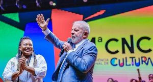 Lula falando e gesticulando em evento, com microfone