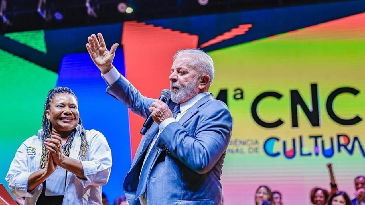 Lula falando e gesticulando em evento, com microfone