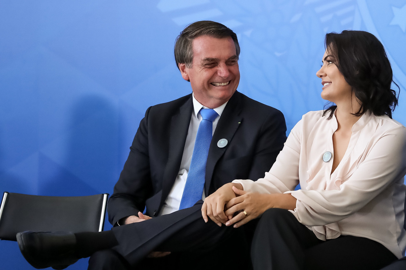 Jair e Michelle Bolsonaro conversando e rindo, sentados lado a lado