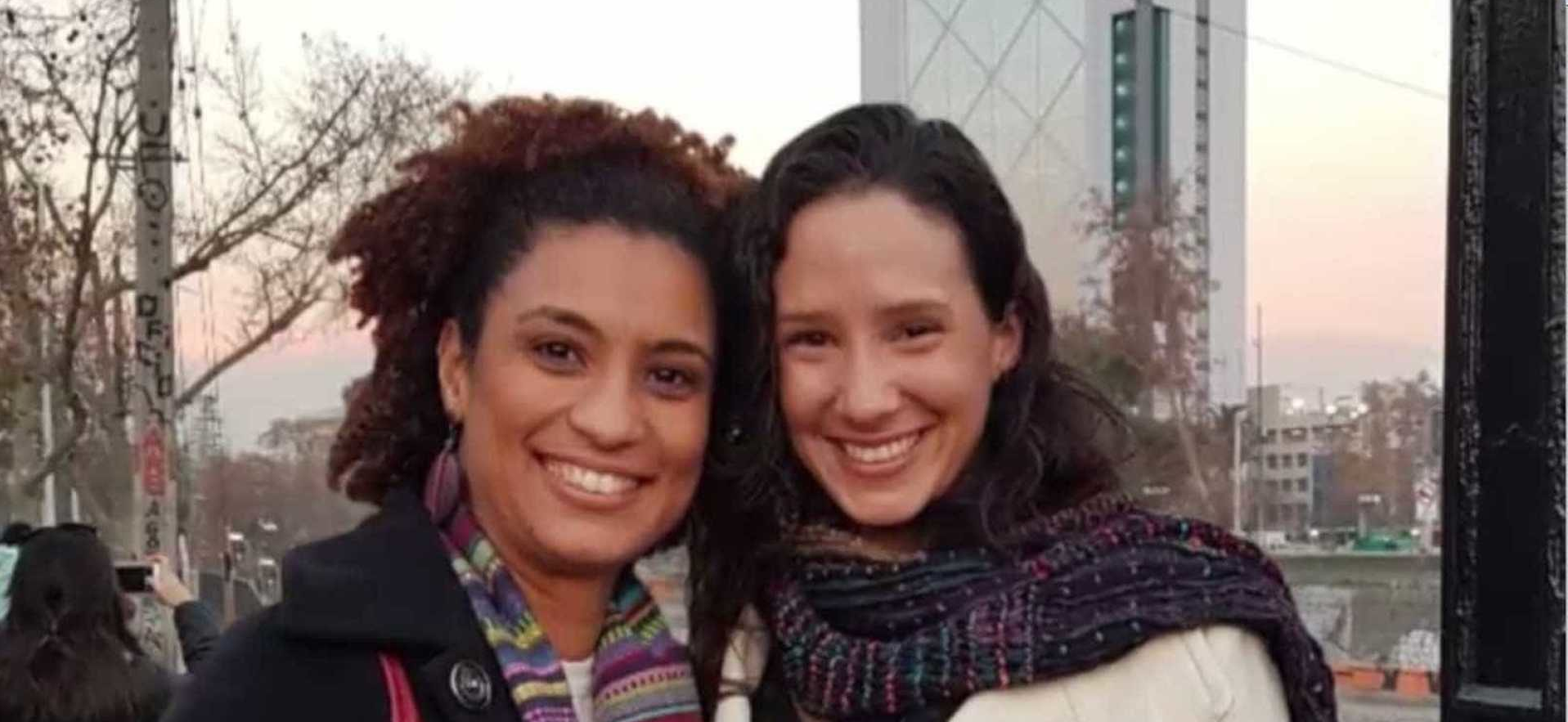 Marielle Franco e Monica Benicio posando lado a lado para foto, as duas sorrindo e com roupas de frio