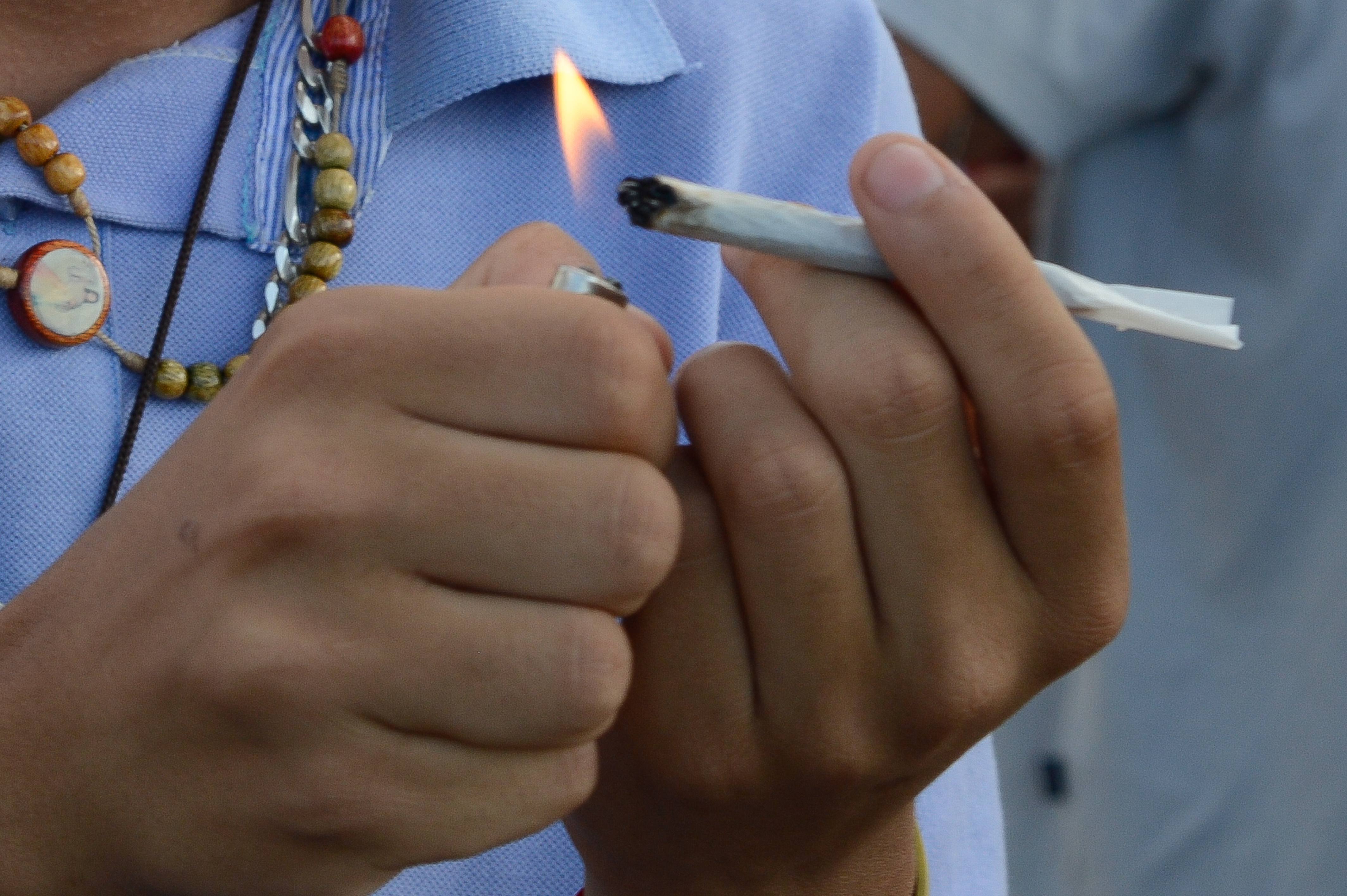 Mãos segurando e acendendo cigarro de maconha