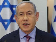 Benjamin Netanyahu falando com bandeiras de Israel atrás