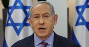 Benjamin Netanyahu falando com bandeiras de Israel atrás