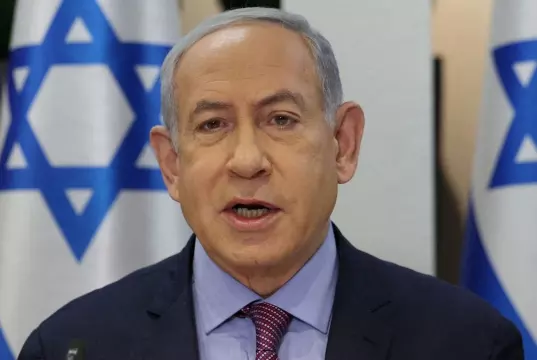 Benjamin Netanyahu falando com bandeiras de Israel atrás