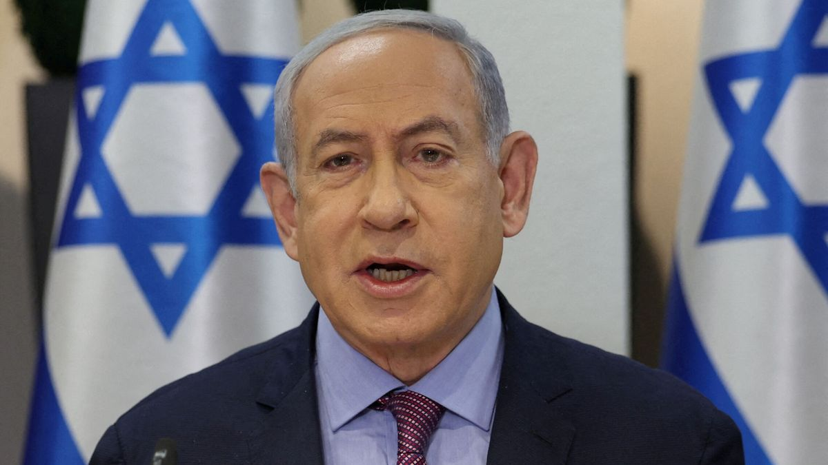 Benjamin Netanyahu falando com bandeiras de Israel atrás