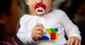 Bebê segurando cartão do Bolsa Família