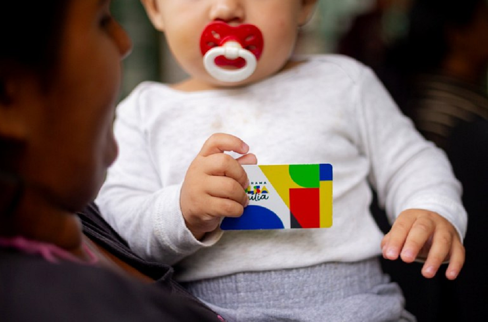 Bebê segurando cartão do Bolsa Família