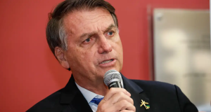 Jair Bolsonaro falando em microfone com expressão séria