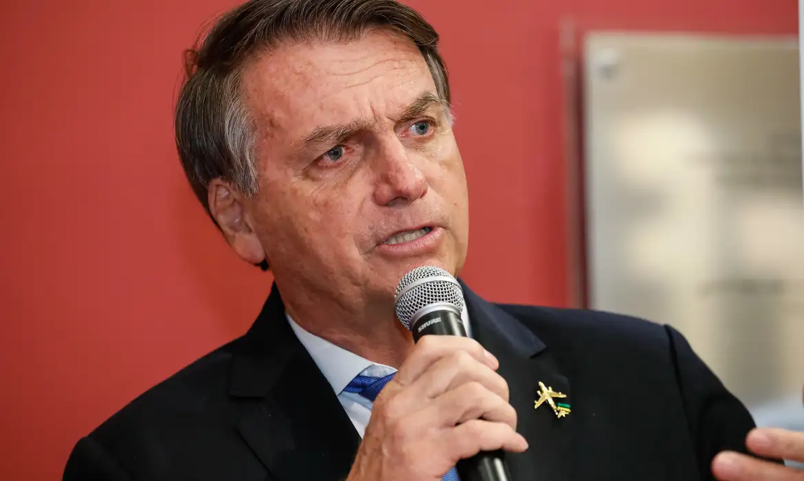 Jair Bolsonaro falando em microfone com expressão séria